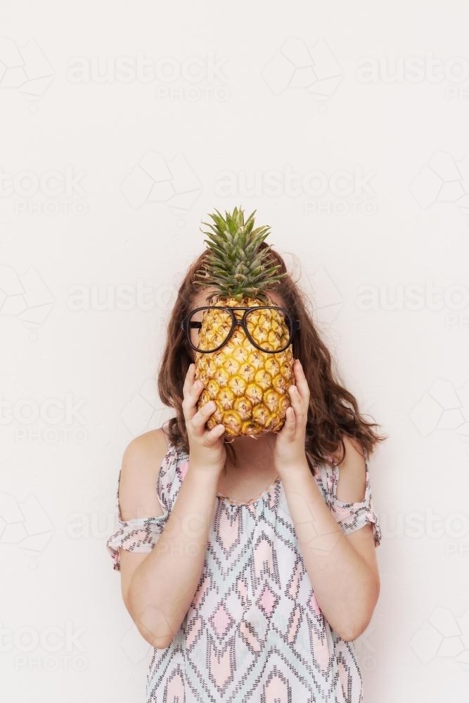 teen girl with pineapple over her face - Australian Stock Image