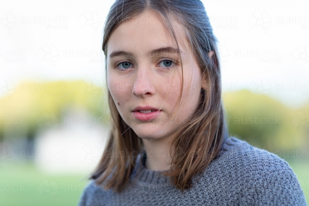 teen girl with shoulder length hair looking at camera without emotion - Australian Stock Image