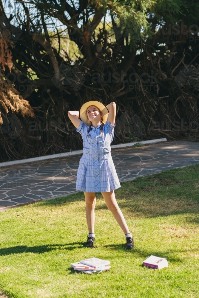 teen high school student girl outside on the grass enjoying the sunshine - Australian Stock Image