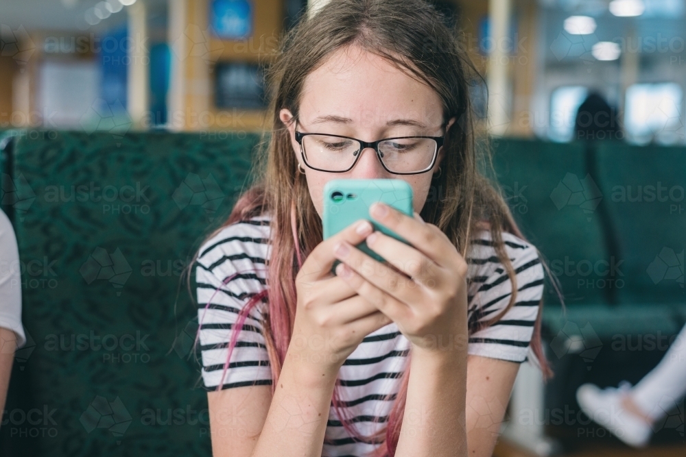 teen looking at photos on her phone - Australian Stock Image