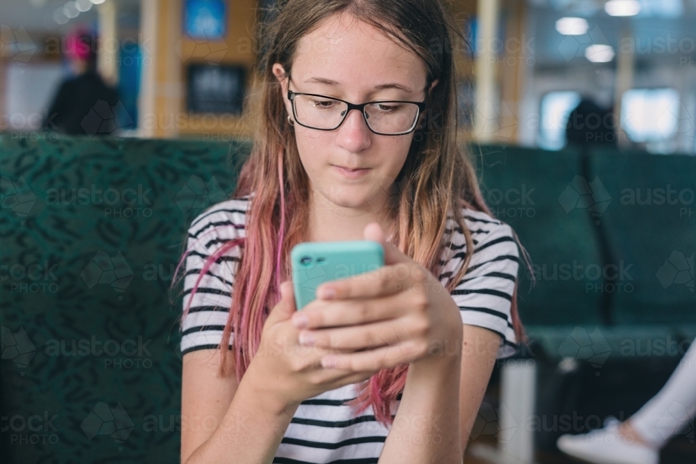teen looking at photos on her phone - Australian Stock Image