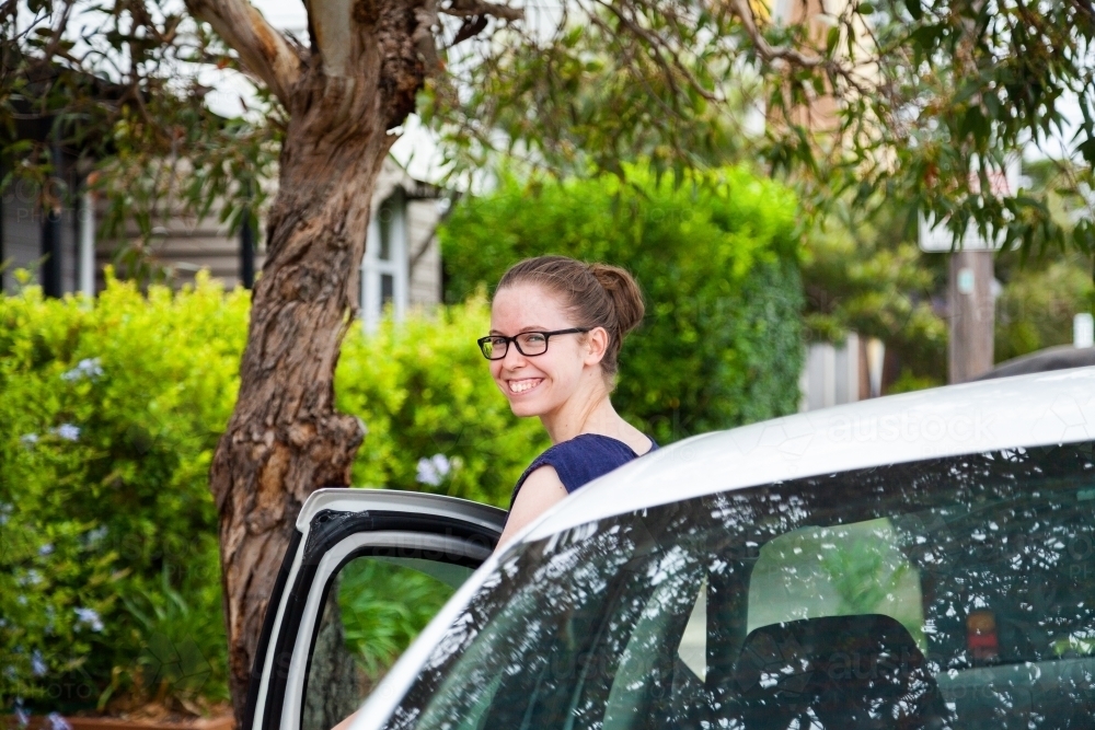 Teen person getting into passenger seat of car - Australian Stock Image