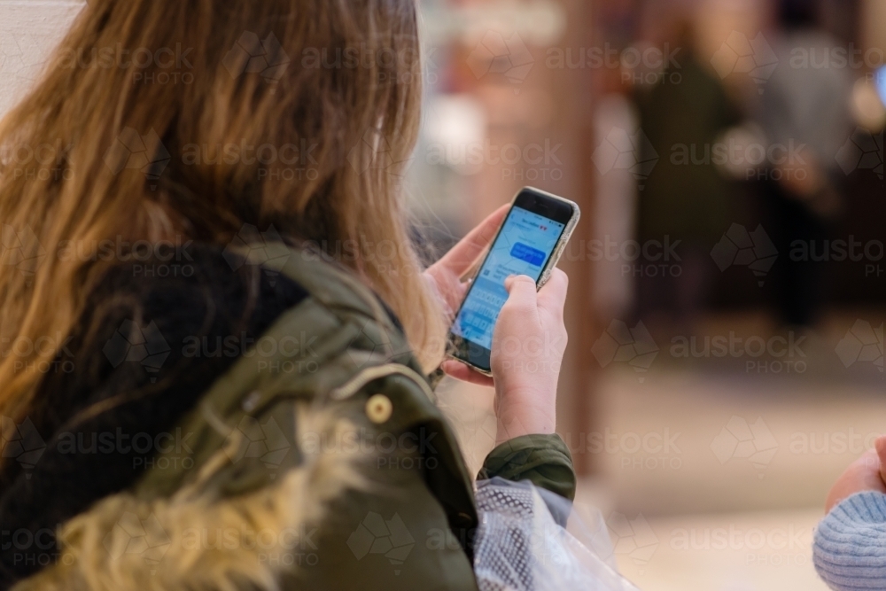 teen using phone at the shopping mall - Australian Stock Image
