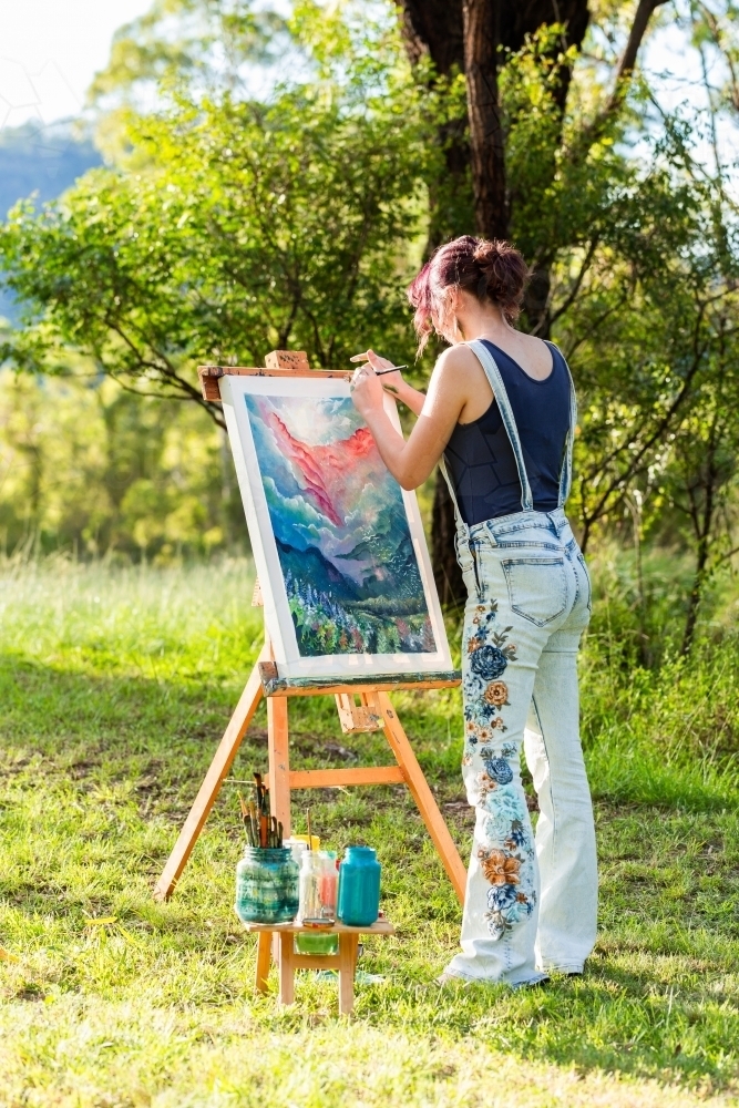 Teenage artist painting in evening sunlight - Australian Stock Image