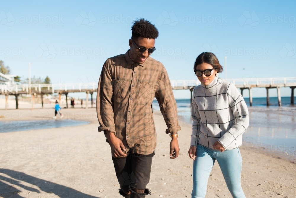 Teenage boy and girl walking on the beach - Australian Stock Image