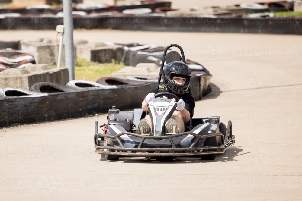 Image of Teenage boy driving go kart around outdoor track - Austockphoto