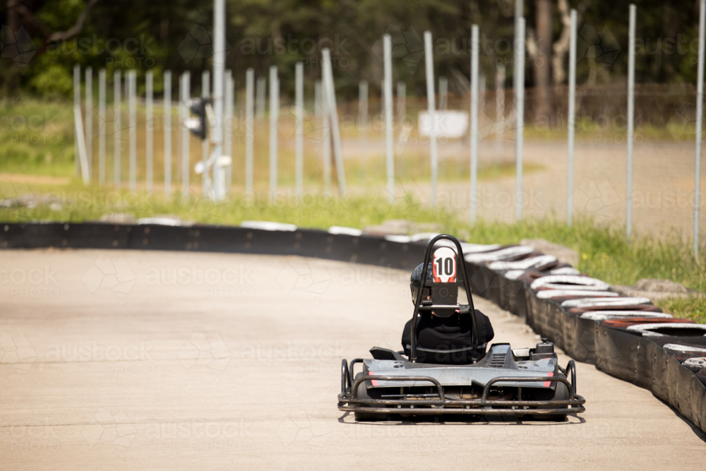 Image of Teenage boy driving go kart around outdoor track - Austockphoto