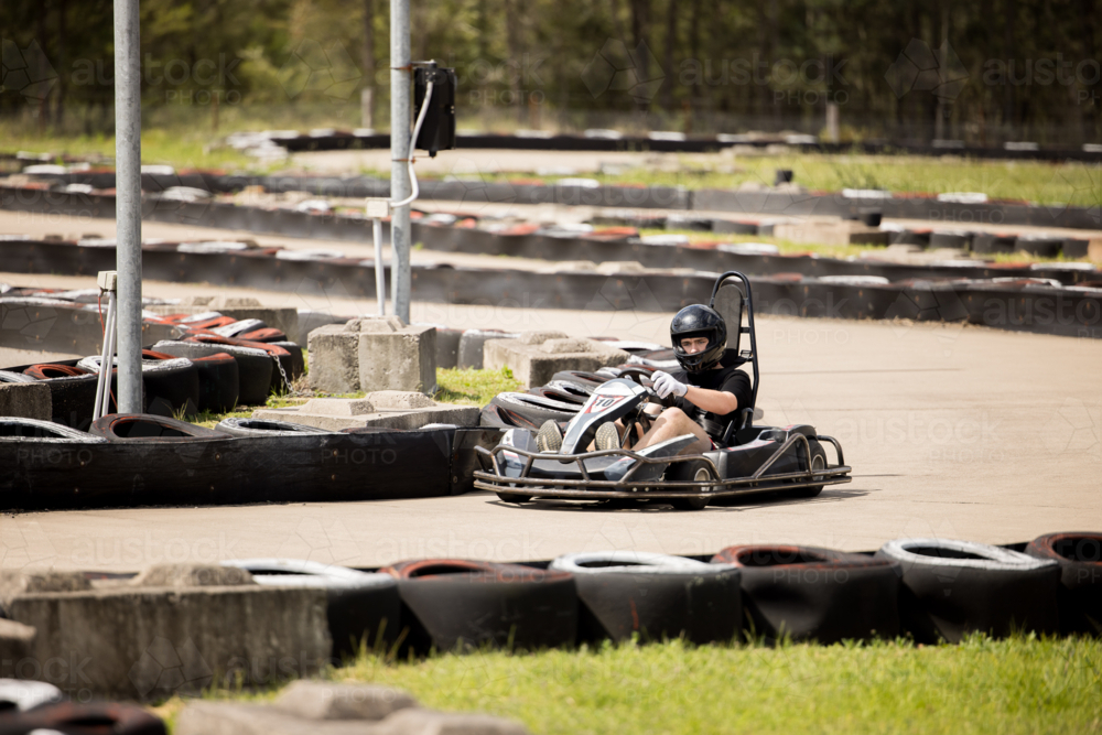 Image of Teenage boy driving go kart around outdoor track - Austockphoto
