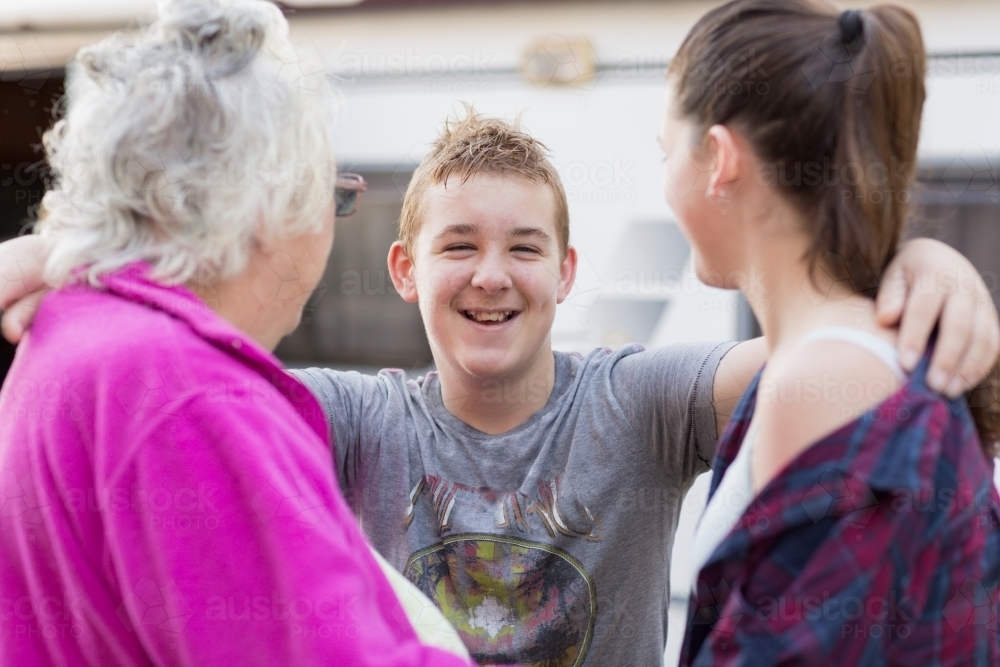 Teenage boy embracing grandmother and sister - Australian Stock Image