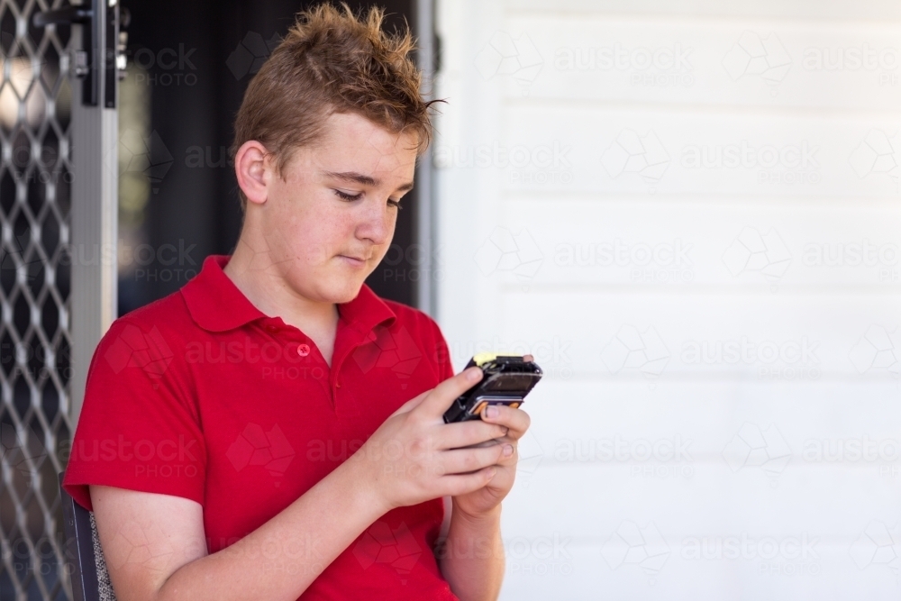 Teenage boy looking at mobile phone - Australian Stock Image