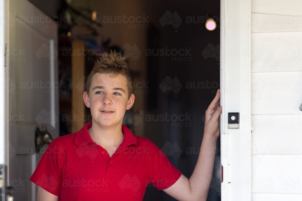 Teenage boy looking out front door - Australian Stock Image