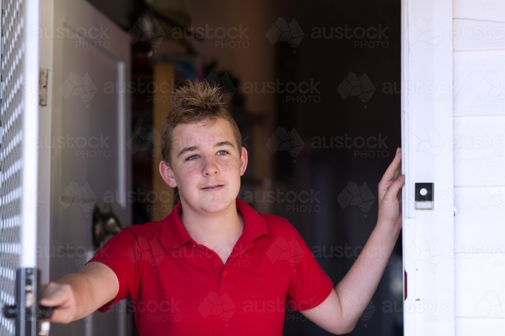 Teenage boy opening front door - Australian Stock Image