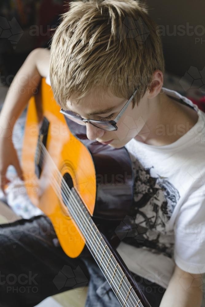 Teenage Boy playing guitar inside - Australian Stock Image