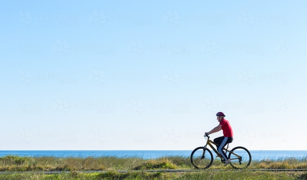 Teenage boy riding a bike on a seaside bike path - Australian Stock Image