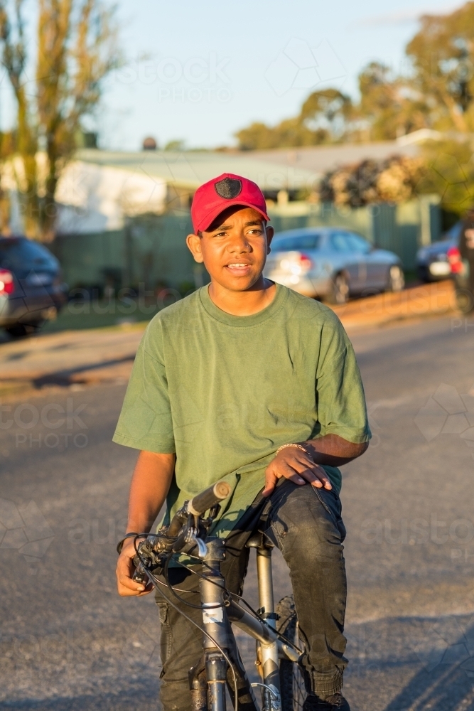 Teenage boy sitting on mountain bike in quiet street - Australian Stock Image
