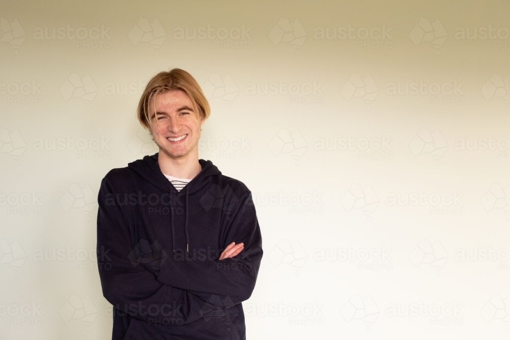 Teenage boy with arms crossed looking at camera - Australian Stock Image
