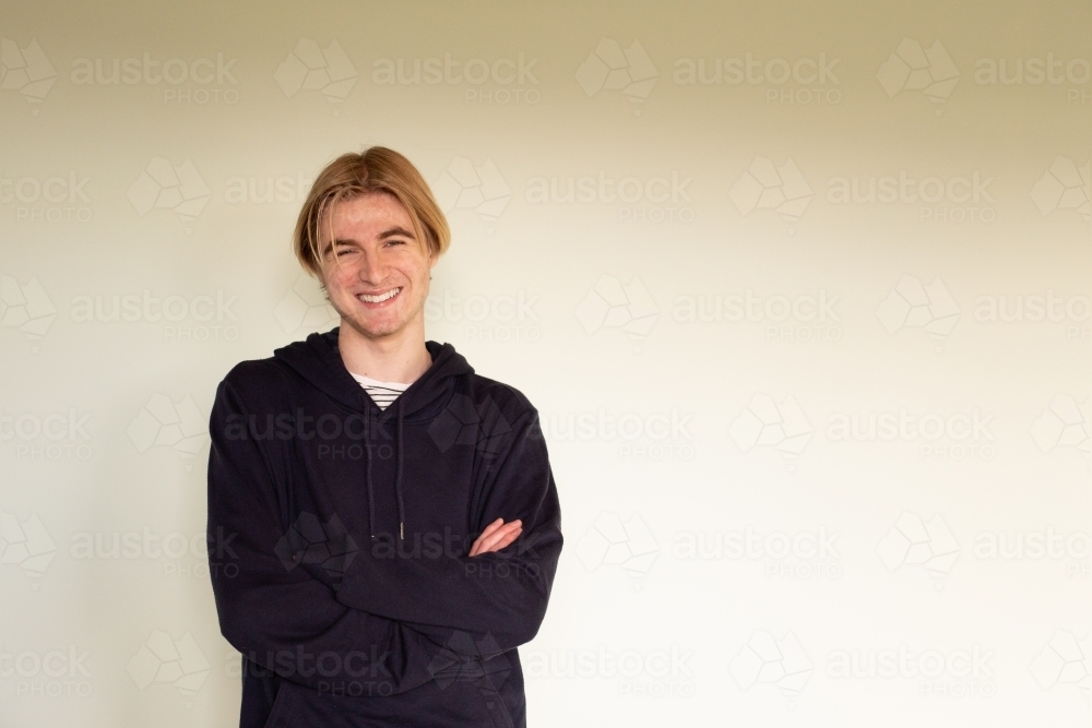 Teenage boy with arms crossed wearing black hoodie - Australian Stock Image