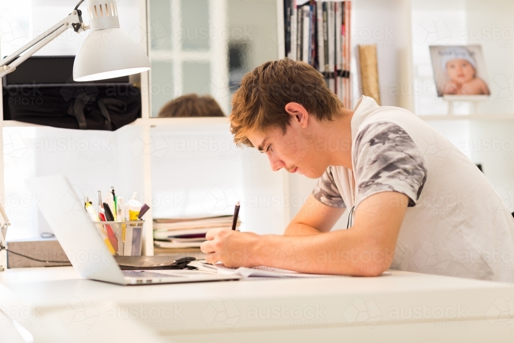 Teenage boy writing at a desk - Australian Stock Image
