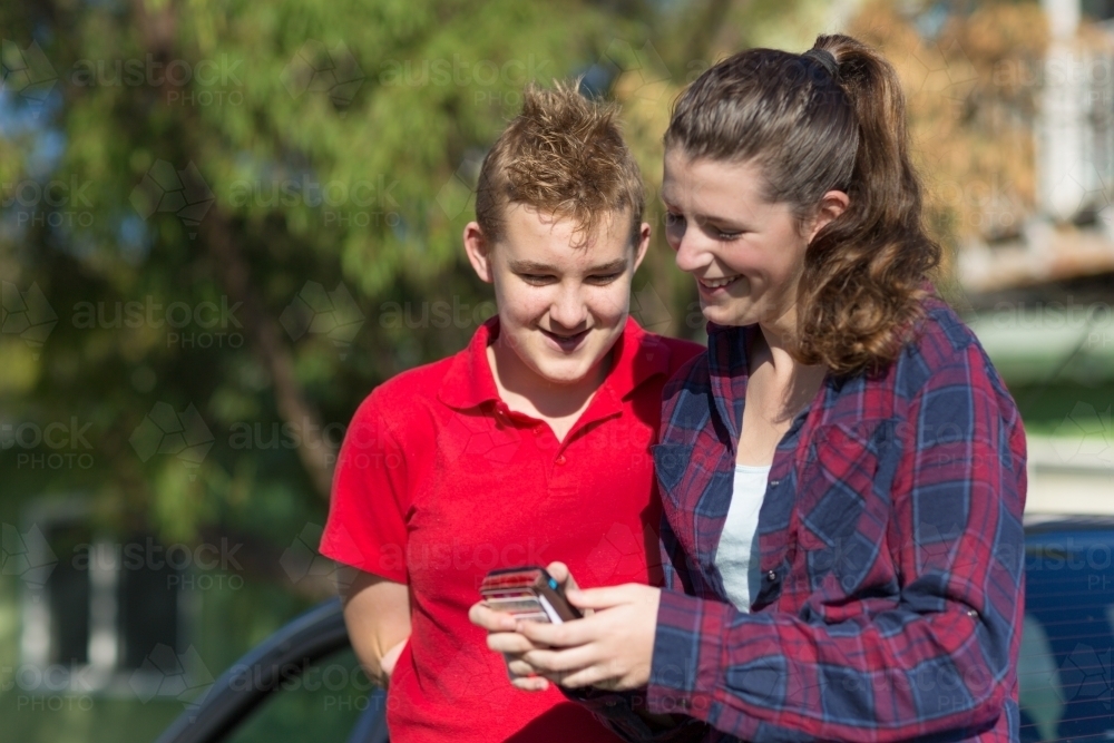 Teenage couple looking at smartphone - Australian Stock Image