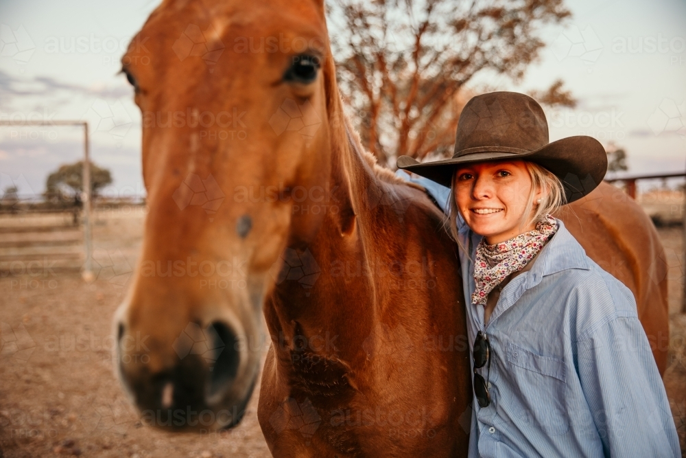 Teenage female smiling beside brown horse - Australian Stock Image