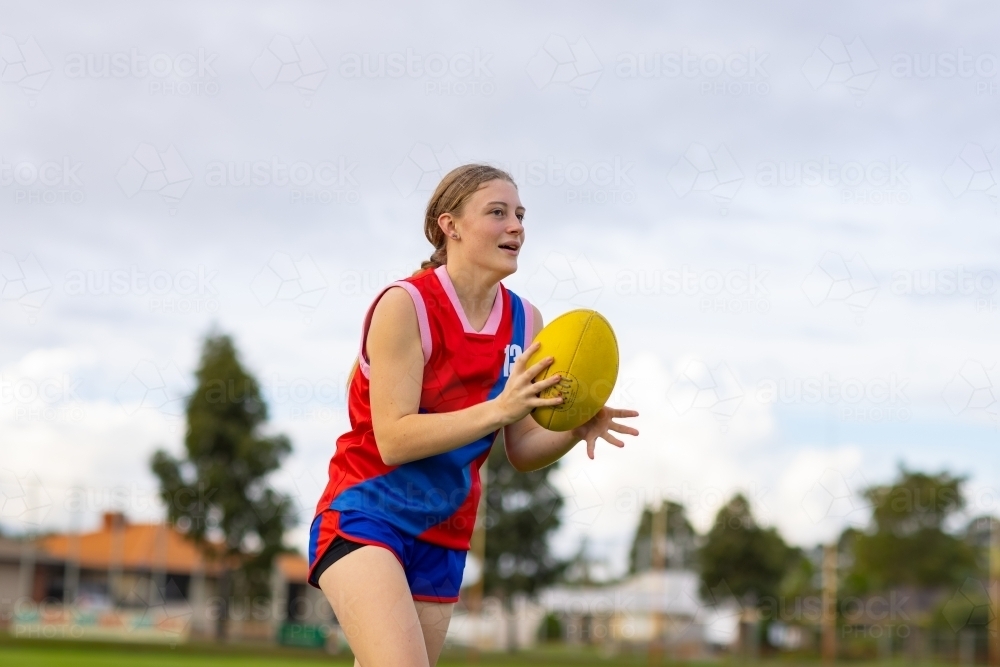 teenage football player holding football during training - Australian Stock Image