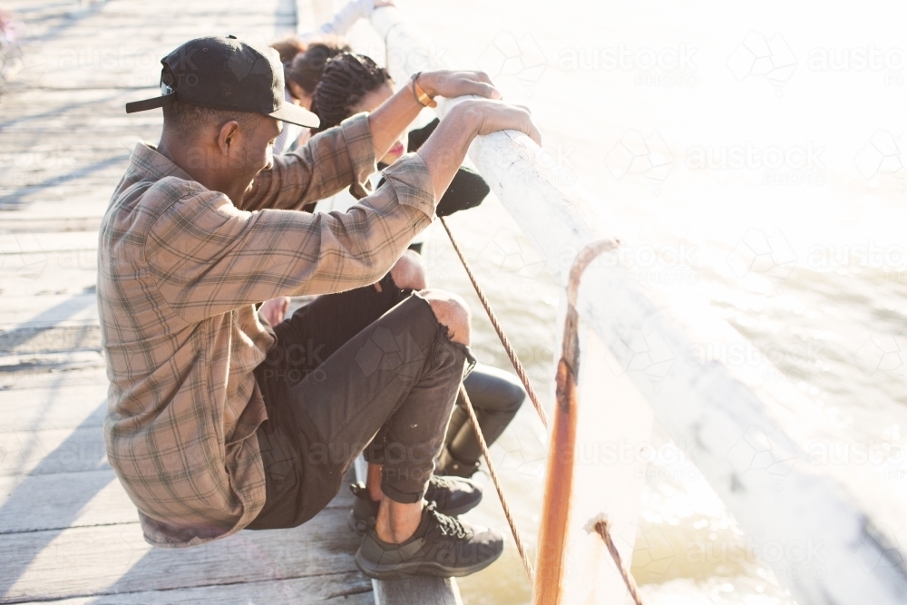 Teenage friends relaxing on a jetty - Australian Stock Image
