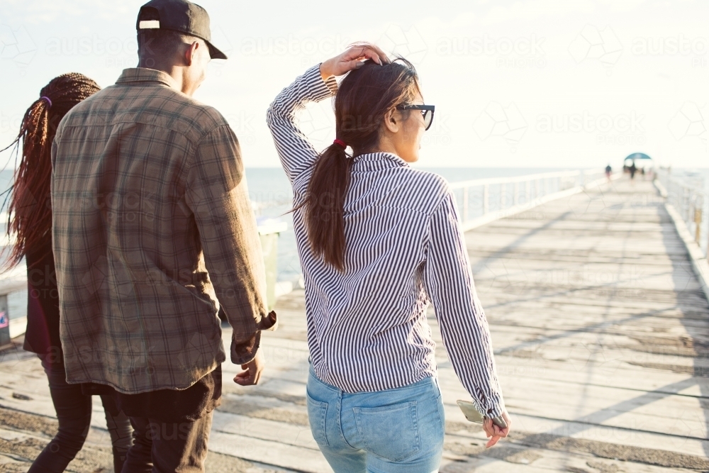 Teenage friends walking along a jetty - Australian Stock Image