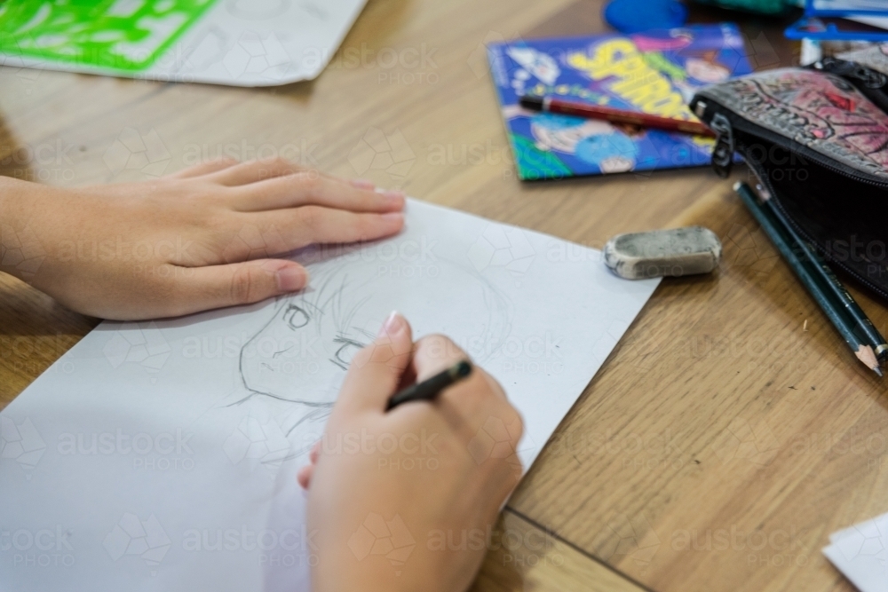 Teenage girl drawing Manga artwork at the table - Australian Stock Image