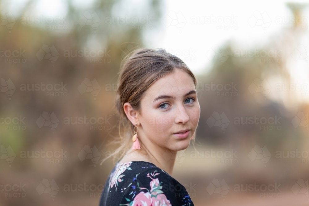 Teenage girl head and shoulders outdoors with blurred background - Australian Stock Image