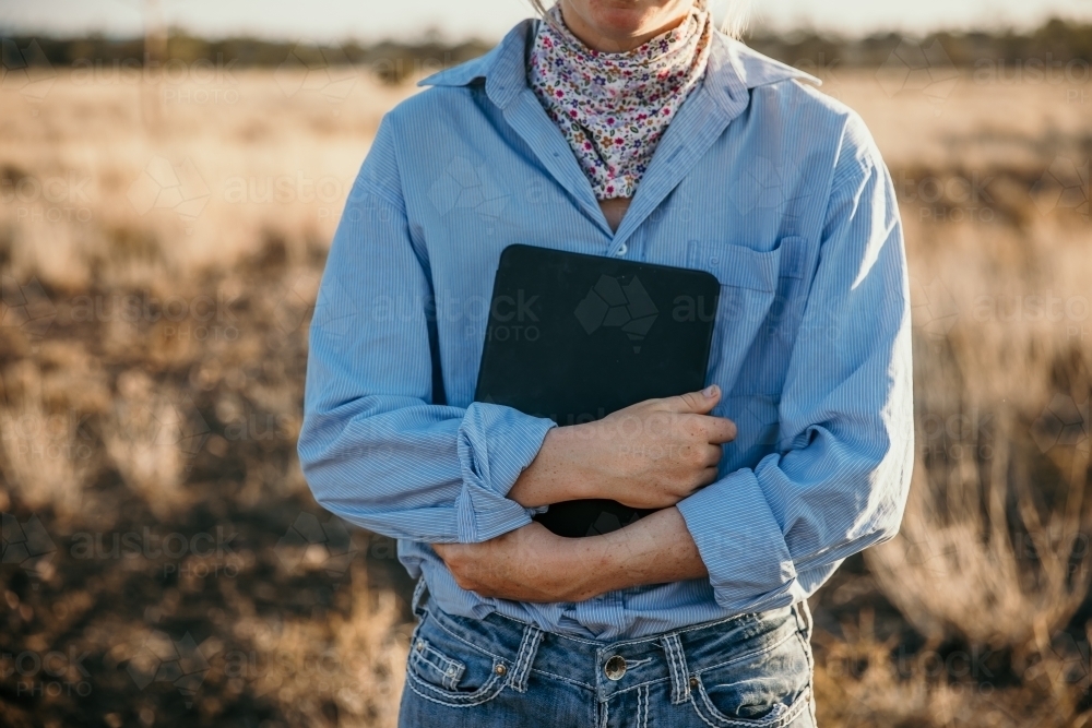 Teenage girl holding her laptop in paddock - Australian Stock Image