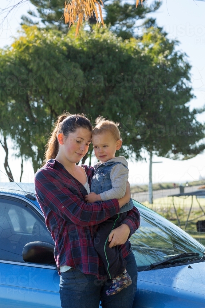 Teenage girl holding toddler outdoors - Australian Stock Image