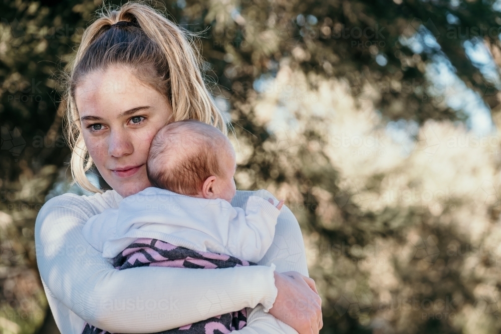 Teenage girl holds her new baby sister. - Australian Stock Image