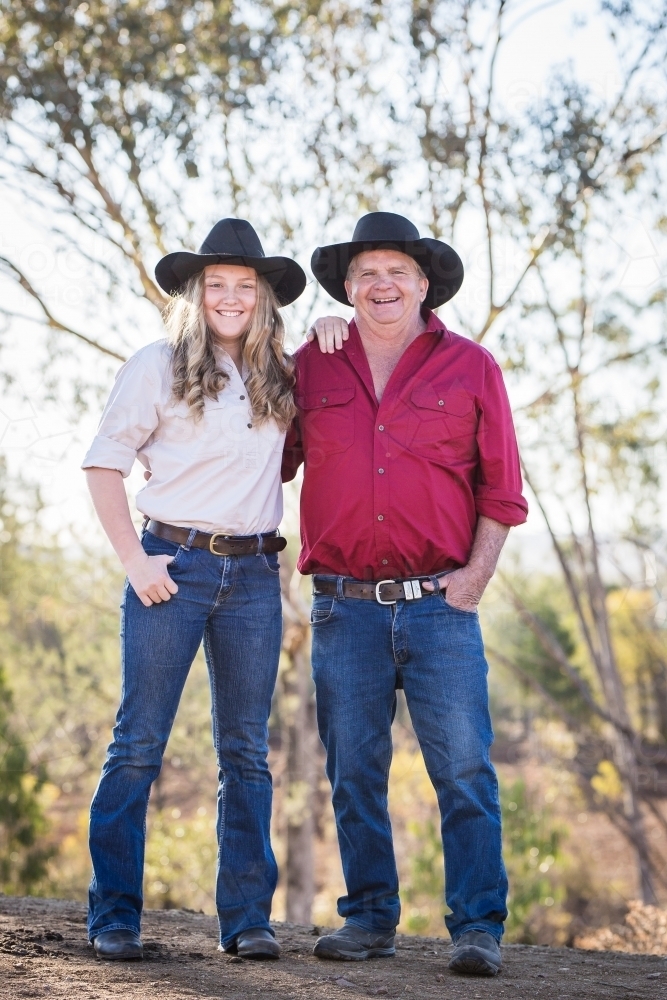 Teenage girl leaning on grandfather's shoulder on family farm in drought - Australian Stock Image