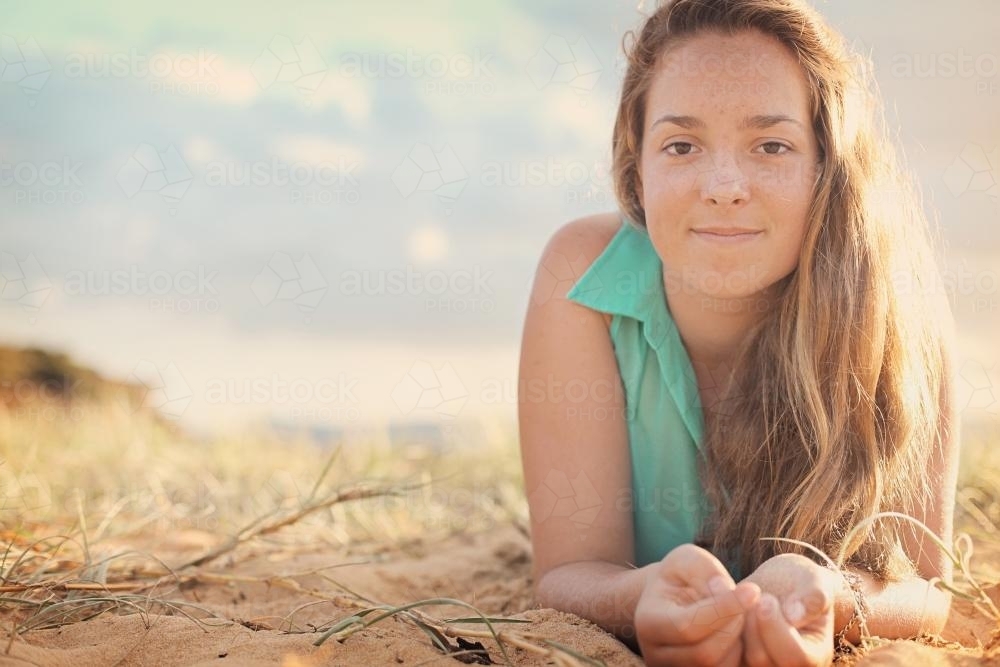 Teenage girl lying on the sand at the beach - Australian Stock Image