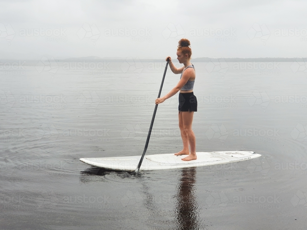 Teenage girl on a stand up paddle board - Australian Stock Image