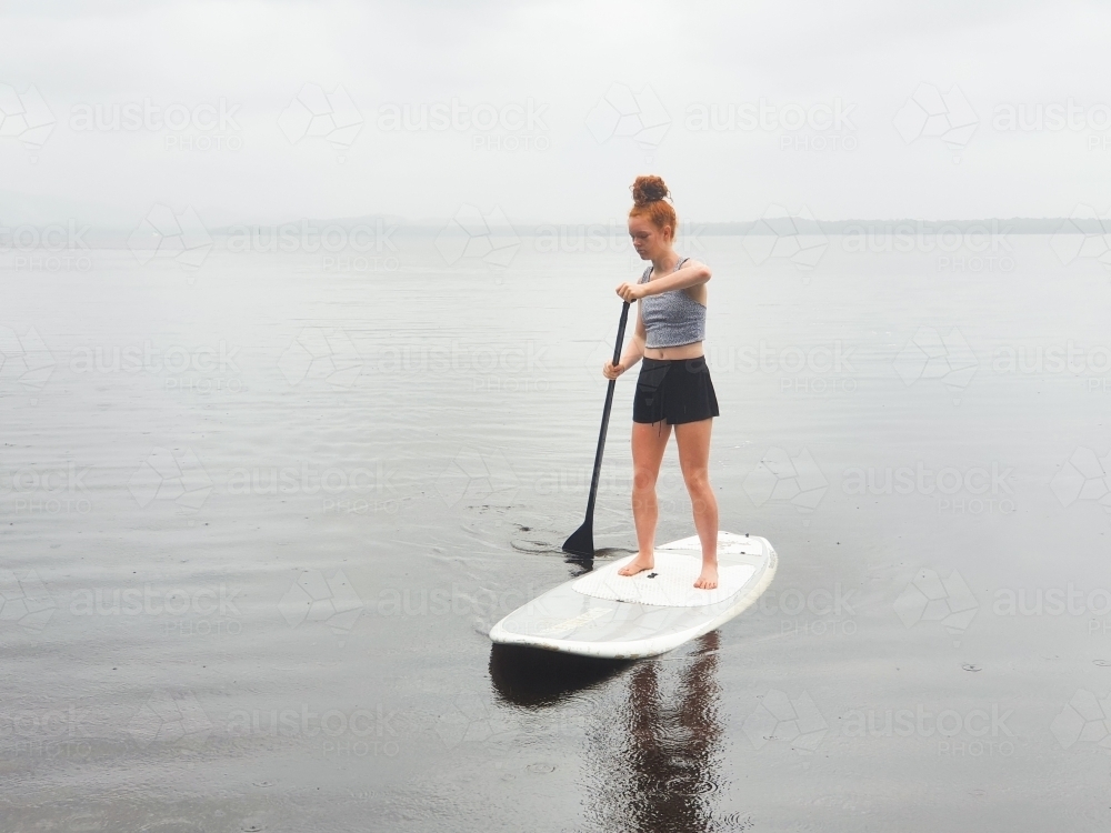 Teenage girl on a stand up paddle board - Australian Stock Image