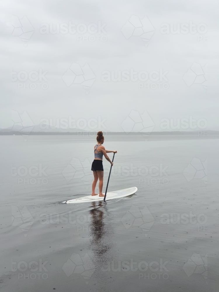Teenage girl on a stand up paddle board - Australian Stock Image