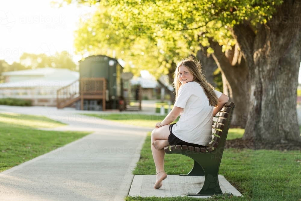 Teenage girl seated on park bench - Australian Stock Image