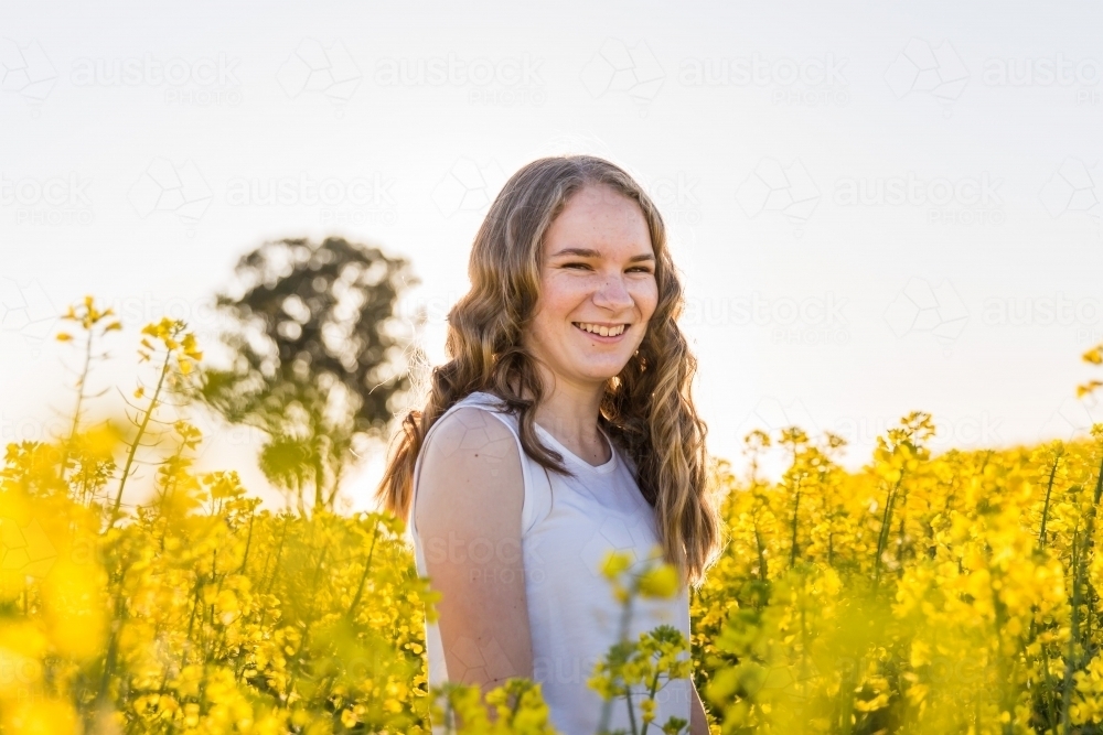 Teenage girl smiling in canola farm - Australian Stock Image