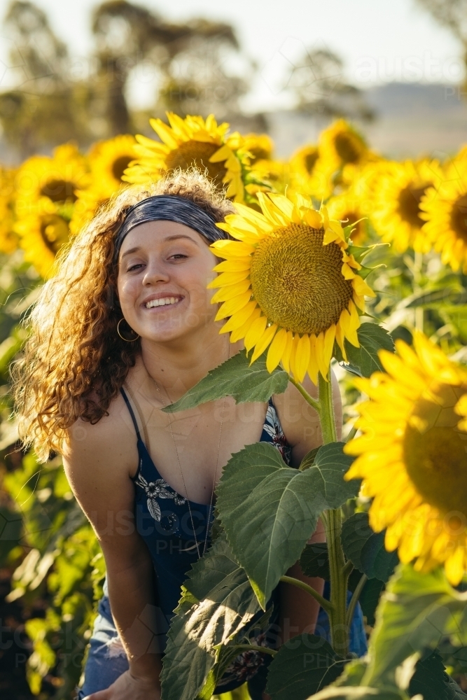 Teenage girl smiling in sunflower field - Australian Stock Image