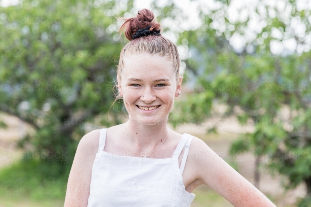 Teenage girl standing in yard at home smiling happy - Australian Stock Image