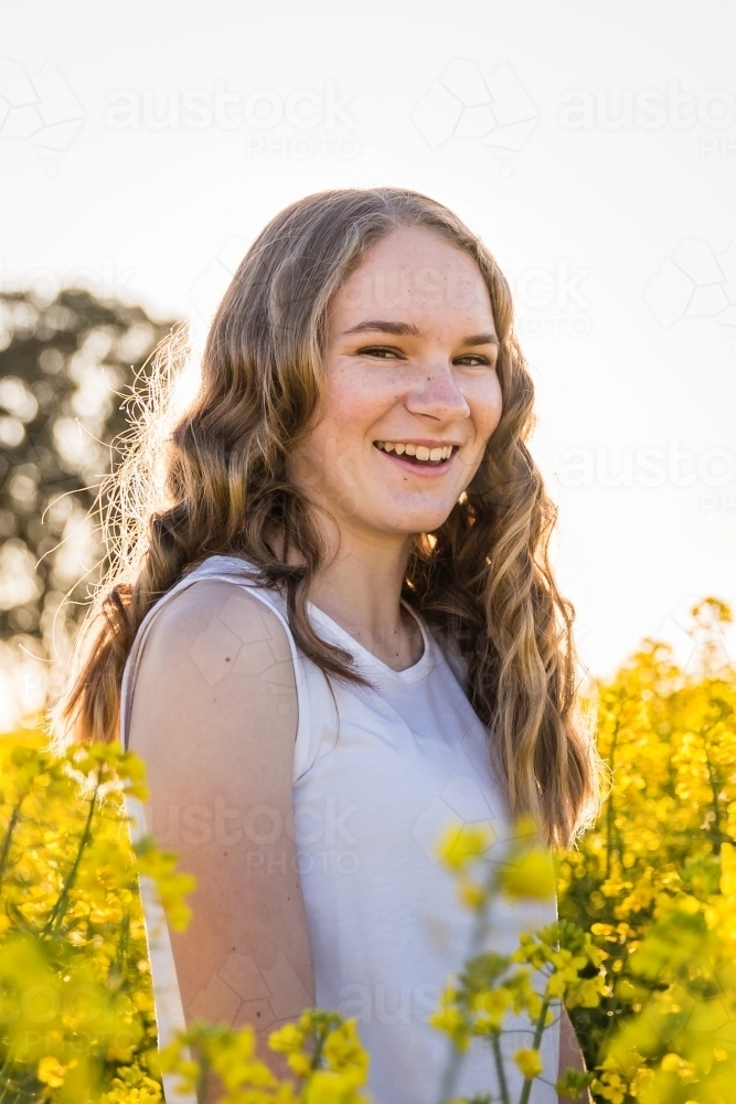 Teenage girl surrounded by canola smiling happy - Australian Stock Image