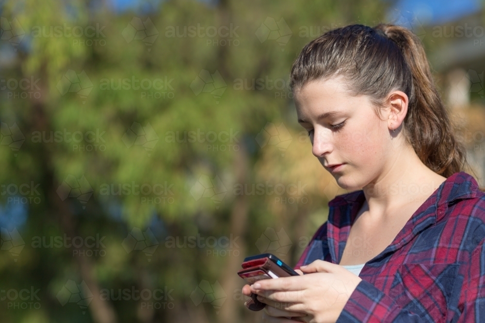 Teenage girl texting on mobile phone - Australian Stock Image