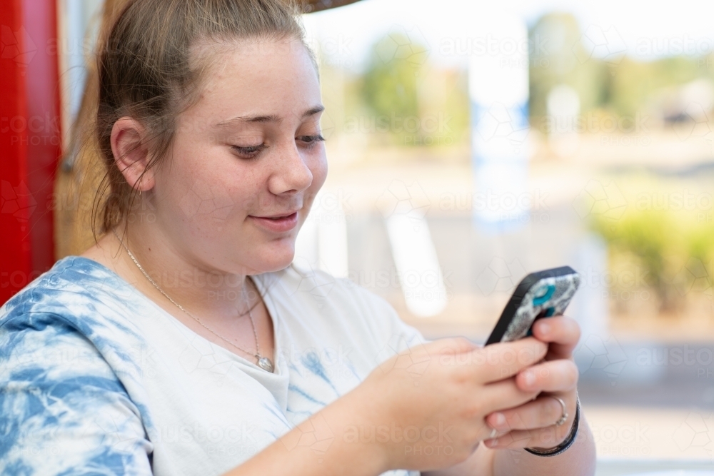 Teenage girl texting on mobile phone - Australian Stock Image