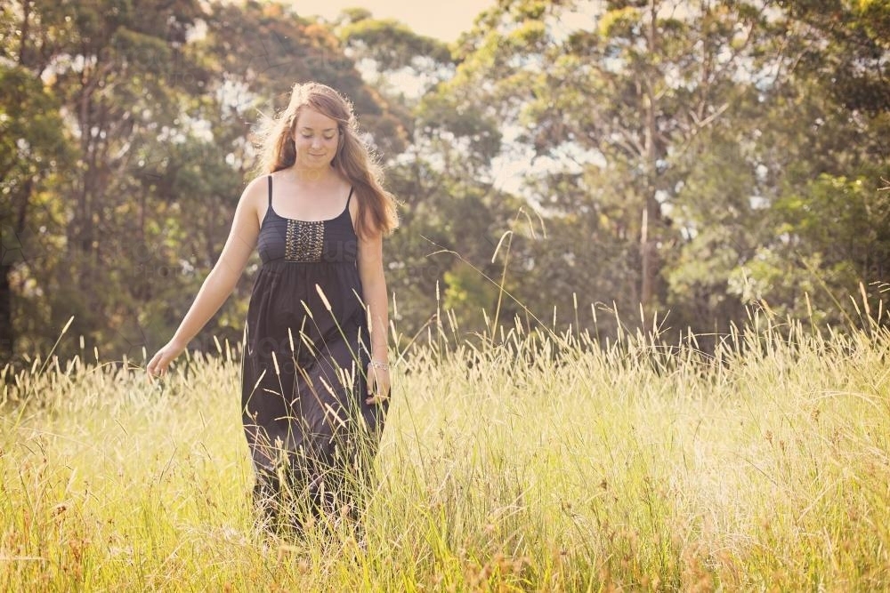 Teenage girl walking through long grass - Australian Stock Image