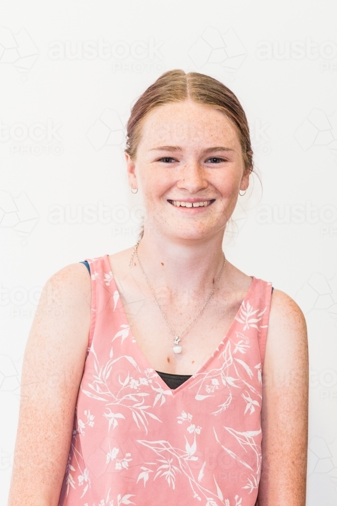 Teenage girl wearing necklace smiling white background - Australian Stock Image