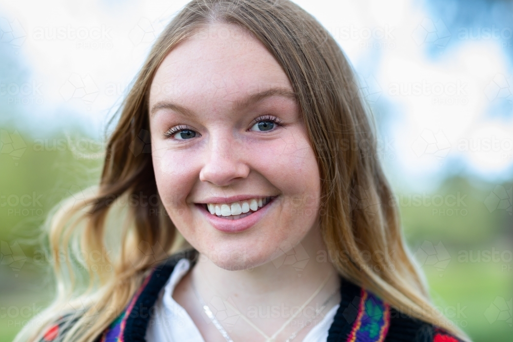teenage girl with long wavy hair smiling while outdoors. - Australian Stock Image