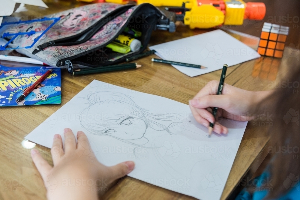 Teenage girls drawing Manga artwork in pencil - Australian Stock Image