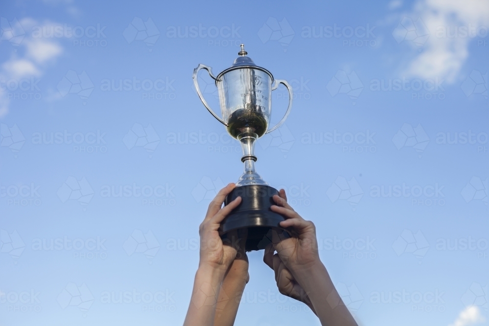Teenage hands holding winning grand final trophy in the sky - Australian Stock Image