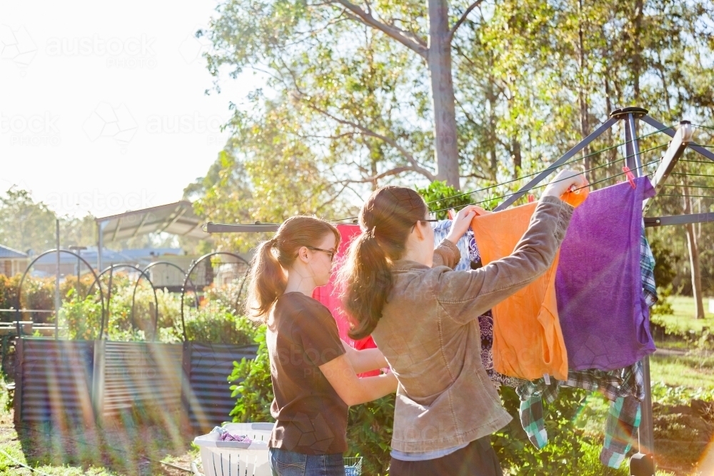 Teenage kids hanging washing up on the clothesline in the backyard - Australian Stock Image